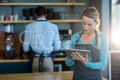 Waitress using digital tablet at counter