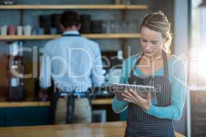 Waitress using digital tablet at counter