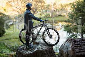 Male mountain biker with bicycle looking at nature