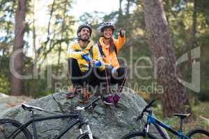 Biker couple sitting on rock and pointing in distance