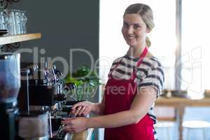 Smiling waitress making cup of coffee in cafÃ?Â©