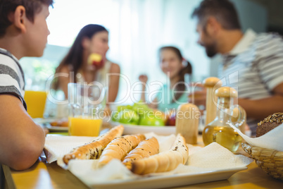 Boy sitting at dinning table with a tray of french bread in front