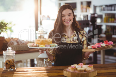 Portrait of waitress standing at counter with desserts