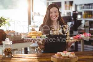 Portrait of waitress standing at counter with desserts