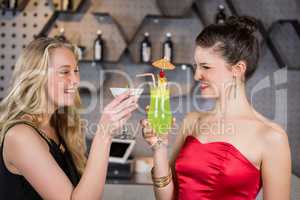 Female friends toasting a glass of cocktail in bar