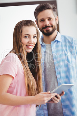 Portrait of happy editors with digital tablet at creative office