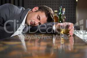 Drunk man lying on a counter with glass of whisky