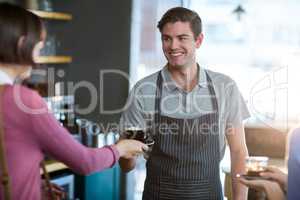 Waiter serving a cup of coffee to customer at counter
