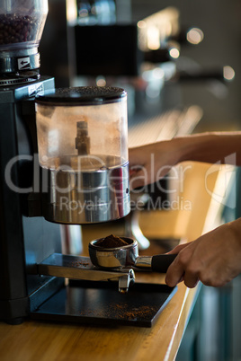 Waiter holding portafilter filled with ground coffee