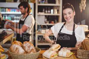 Portrait of waitress standing at counter with sandwiches and bread roll