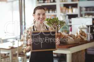 Portrait of waitress showing chalkboard with open sign