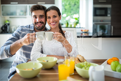 Portrait of couple toasting a cup of coffee while having breakfast