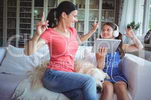 Excited mother and daughter using digital tablet and dancing