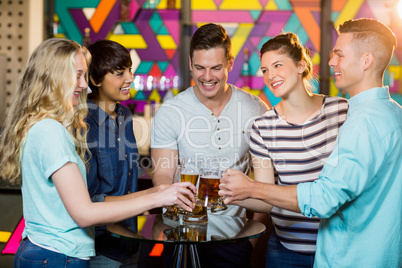 Group of friends toasting glass of beer in party