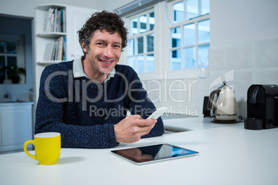 Man holding mobile phone in the kitchen