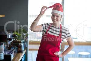 Portrait of waitress in santa hat standing with hand on hip