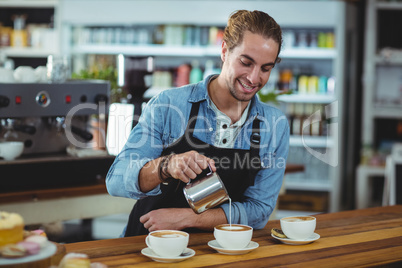 Smiling waiter making cup of coffee at counter