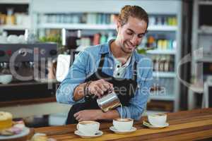 Smiling waiter making cup of coffee at counter