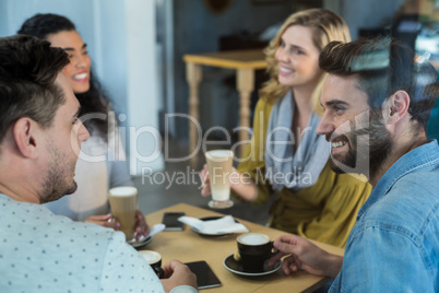 Smiling friends having a cup of coffee and cold coffee in cafÃ?Â©