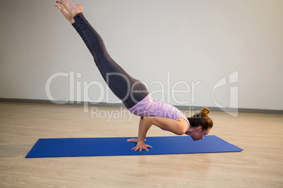 Woman doing arm balance pose on exercise mat