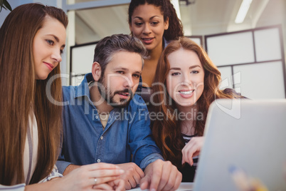 Creative business people using laptop at desk