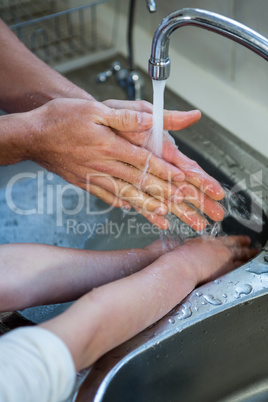 Father and son washing hands in the kitchen sink