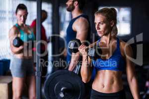Confident woman holding dumbbells in gym