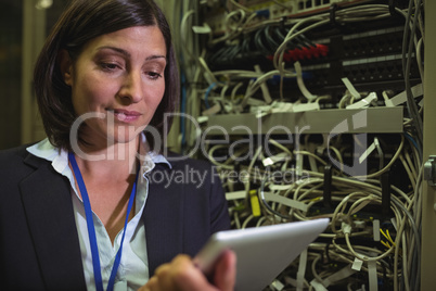 Technician using digital tablet while analyzing server