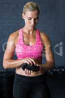 Female athlete removing gloves against wall in gym