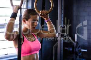 Young woman holding gymnastic rings in gym