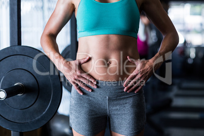 Midsection of female athlete touching belly in gym