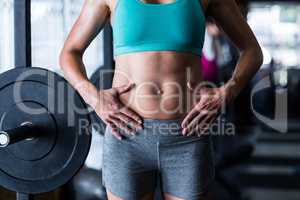 Midsection of female athlete touching belly in gym