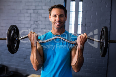 Smiling man exercising with barbell