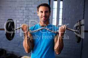 Smiling man exercising with barbell