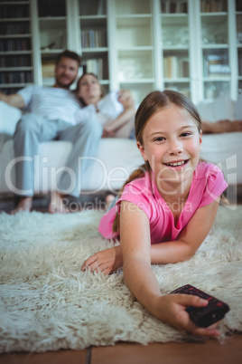 Smiling girl lying on rug and changing channels