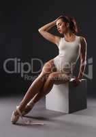 Ballerina sitting and her pointe shoe untied