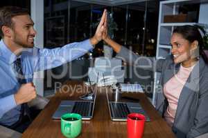 Business executives giving high fives while working in office