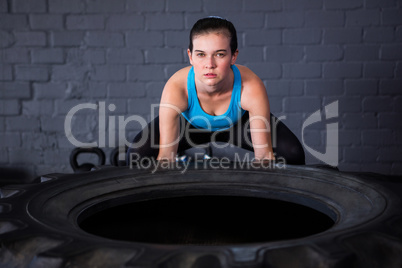 Portrait of serious female athlete picking up tire