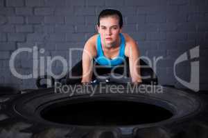 Portrait of serious female athlete picking up tire