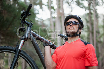 Male mountain biker carrying bicycle in the forest