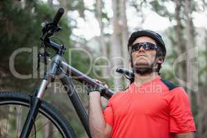 Male mountain biker carrying bicycle in the forest