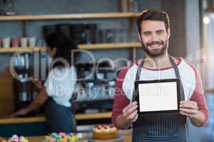 Smiling waiter showing digital tablet at counter in cafÃ?Â©