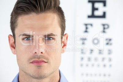 Man wearing contact lens with eye chart in background