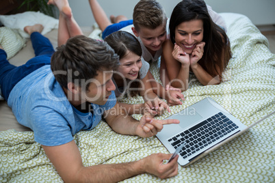 Family doing online shopping on laptop in bedroom