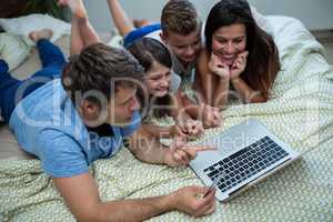 Family doing online shopping on laptop in bedroom