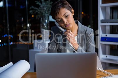 Businesswoman talking on phone while working in office