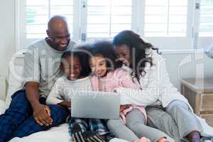 Family using laptop on bed