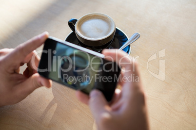 Female hands photographing a coffee cup
