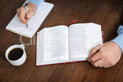Man with a bible writing on notepad