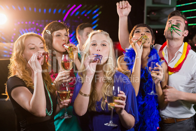 Group of friends blowing party horn in bar
